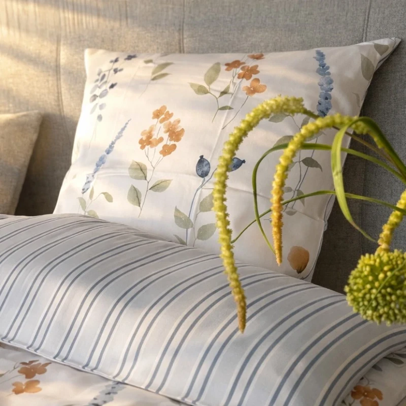 Blomstret og stribet sengetøj blå på redt seng